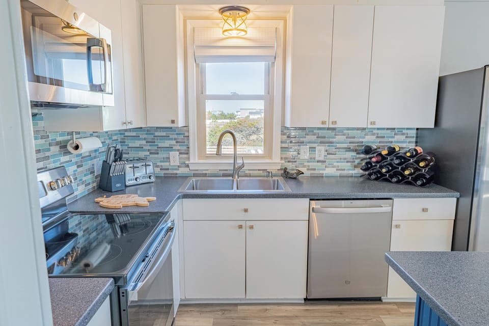 Bright kitchen with stainless appliances, wine rack, and window view