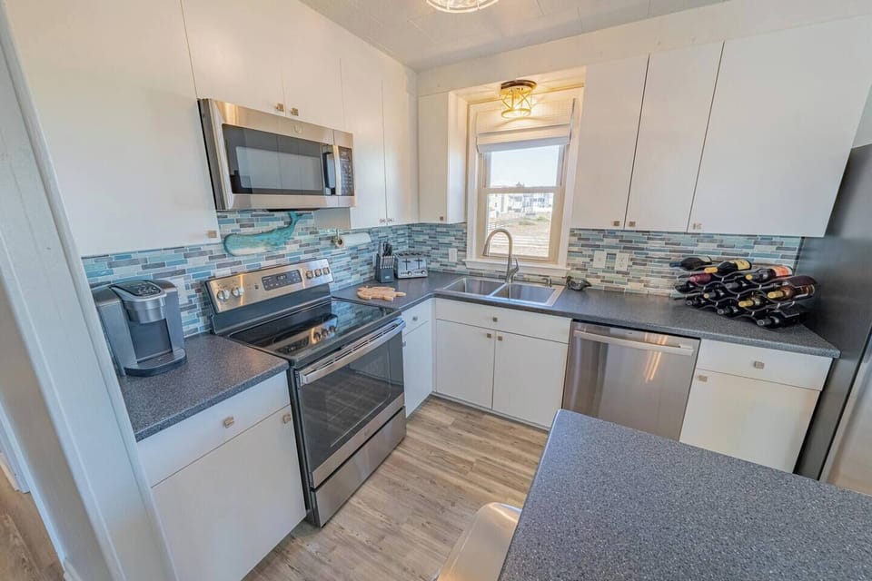 Bright kitchen with stainless appliances, mosaic backsplash, wine rack.