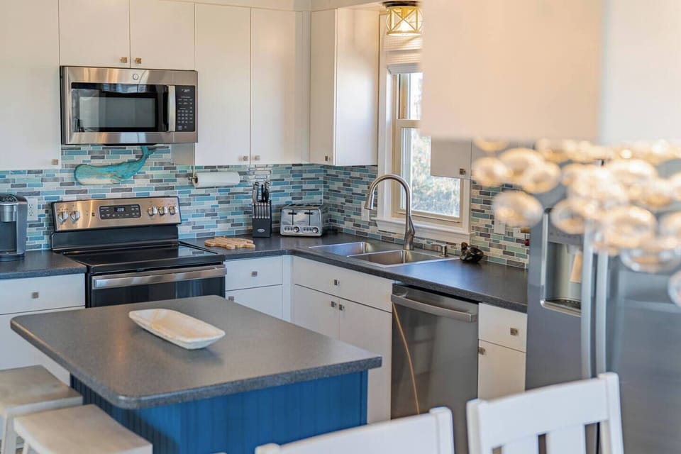 Bright kitchen with island, stainless appliances and mosaic backsplash