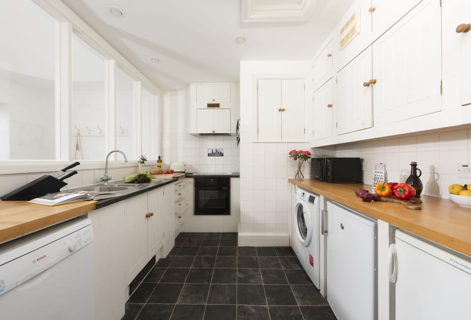 Acton Castle, Marazion. Upper Ground Floor: Kitchen with an electric oven and hob, fridge, freezer, dishwasher, microwave, and washing machine