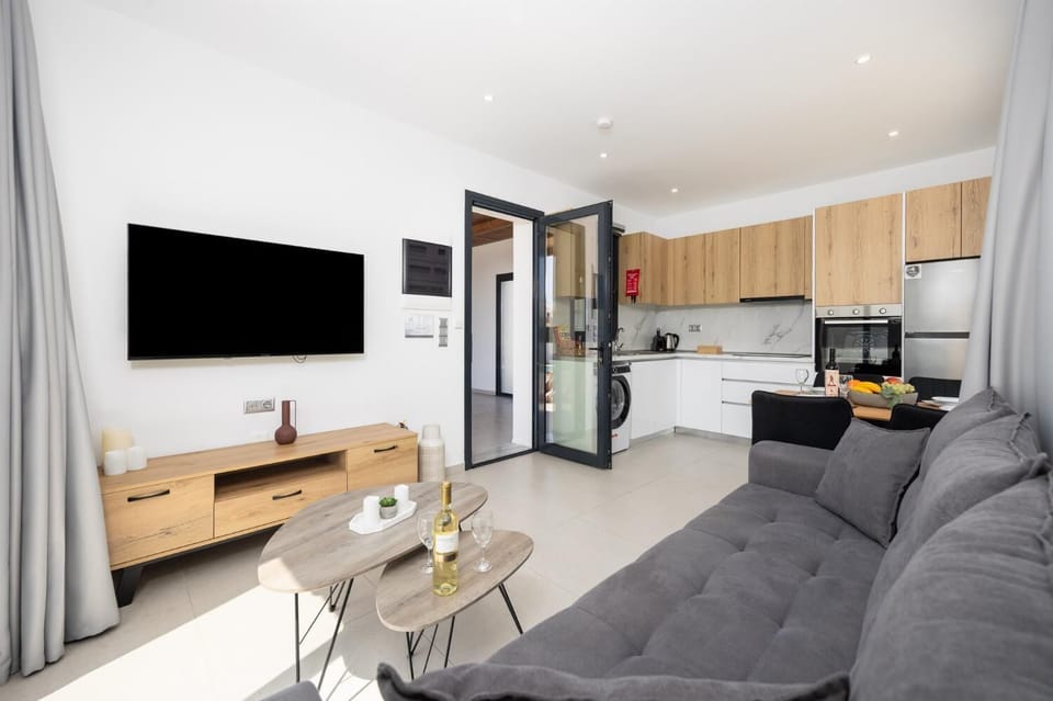 Open-plan living room with sofa, dining area, kitchen, A/C, WiFi internet, and satellite TV