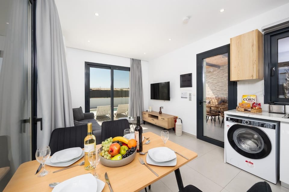 Open-plan living room with sofa, dining area, kitchen, A/C, WiFi internet, and satellite TV