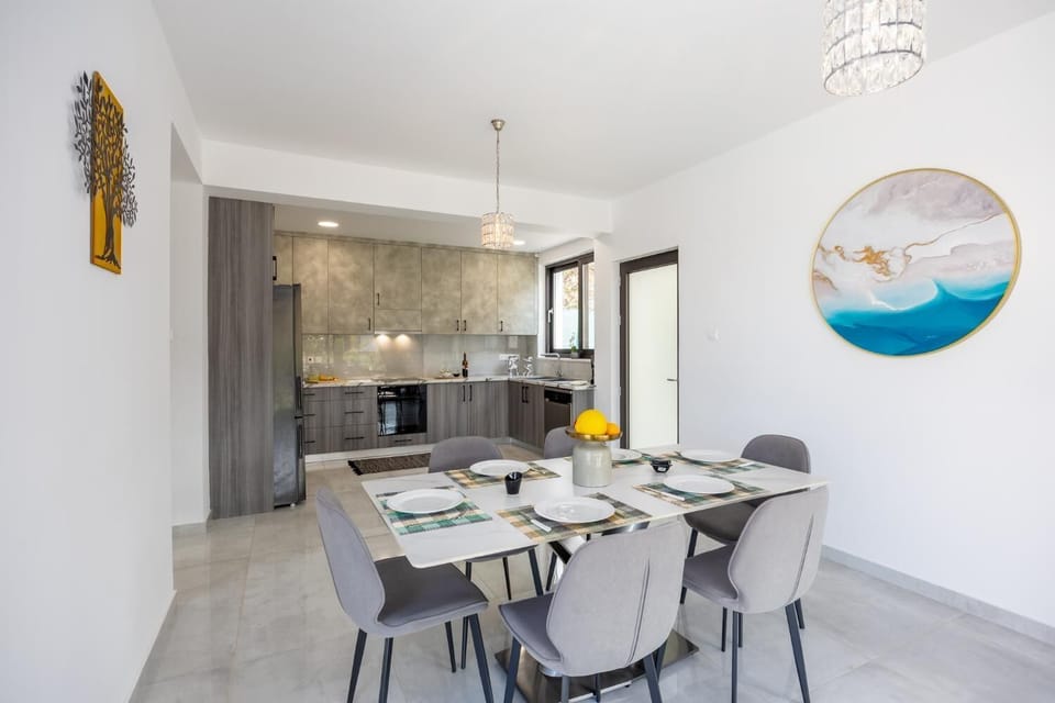 Bright dining area with elegant grey seating, modern kitchen, and stylish wall art.