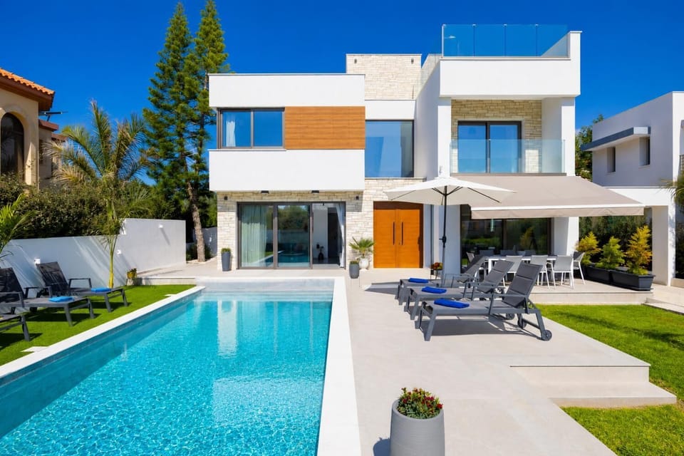 Modern luxury villa with a private pool, sun loungers, and a bright landscaped garden.
