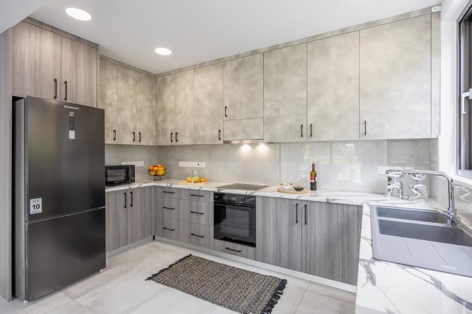Modern grey kitchen with marble-style worktops, full appliances, and a clean elegant design.