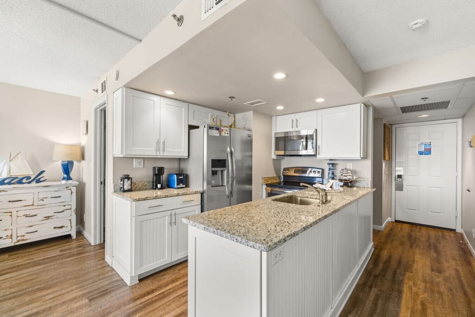 Fully equipped coastal kitchen with breakfast bar seating and modern stainless steel appliances