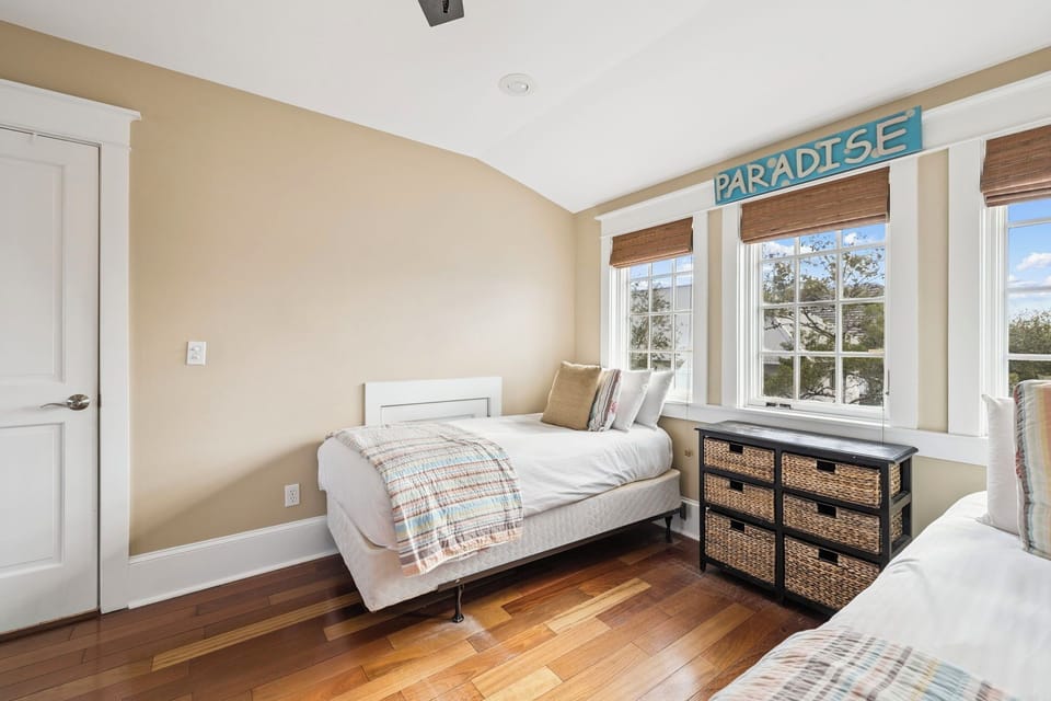Drift off in this bright twin bedroom where morning light streams through charming windows and cozy coastal vibes invite peaceful dreams.