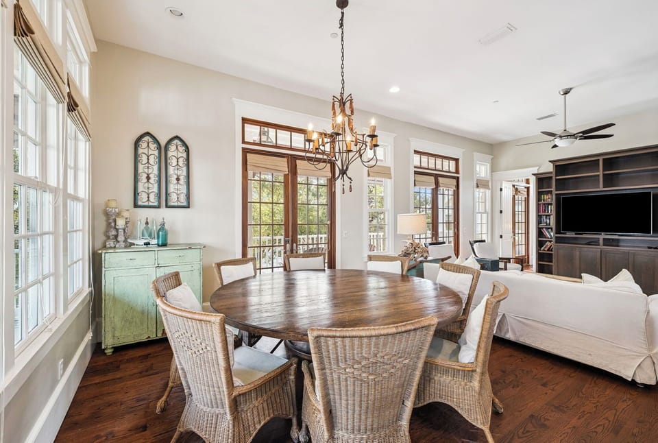 Your elegant dining space features a stunning round table, wicker chairs, and French doors opening to outdoor tranquility.