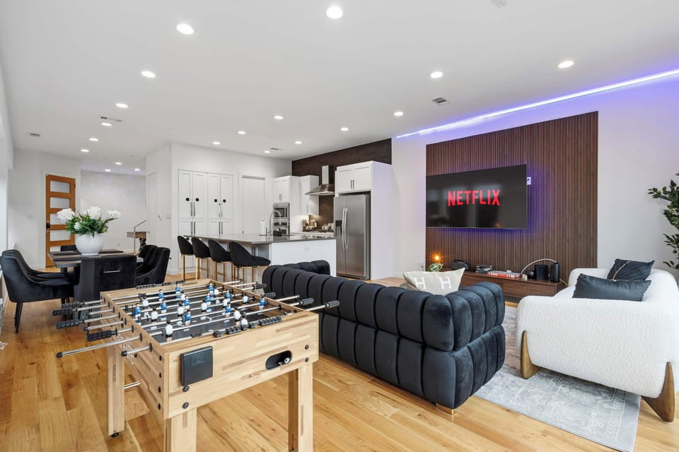 Stylish living room featuring a large sectional sofa, Smart TV, and game table for added fun. Perfect for movie nights, relaxing after exploring the city, or spending quality time together.
