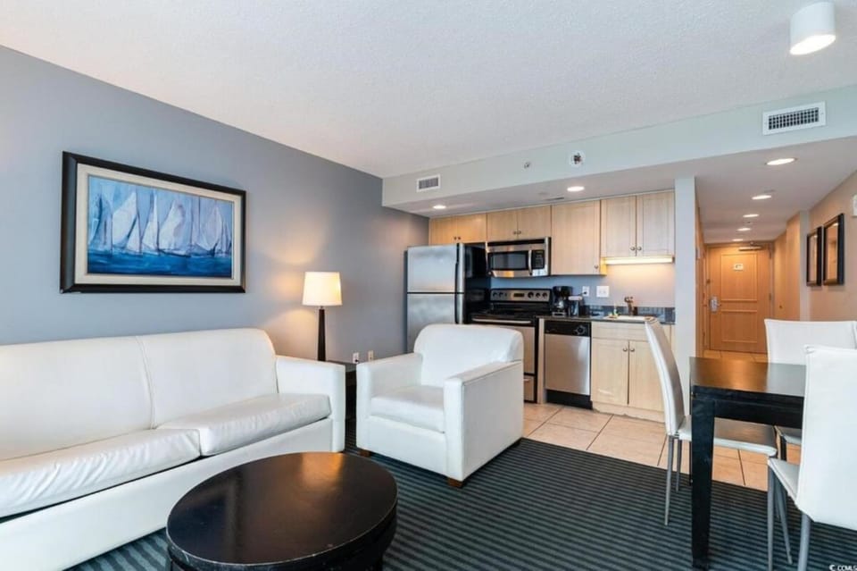 Open living room with plush sofa, TV, and dining area