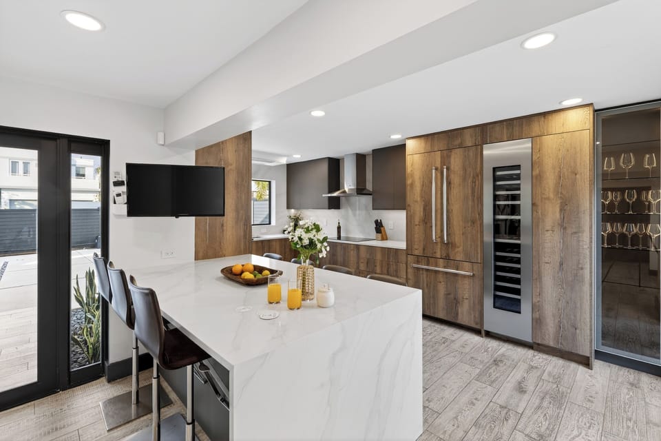 Chef-worthy kitchen with a sleek waterfall island, bar seating, and a built-in wine fridge—made for gathering.