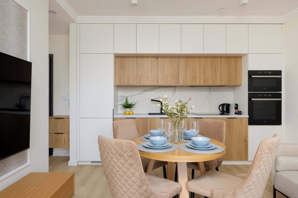 The sleek kitchen combines white and wood-textured cabinets, equipped with high-end built-in appliances and a minimalist backsplash.