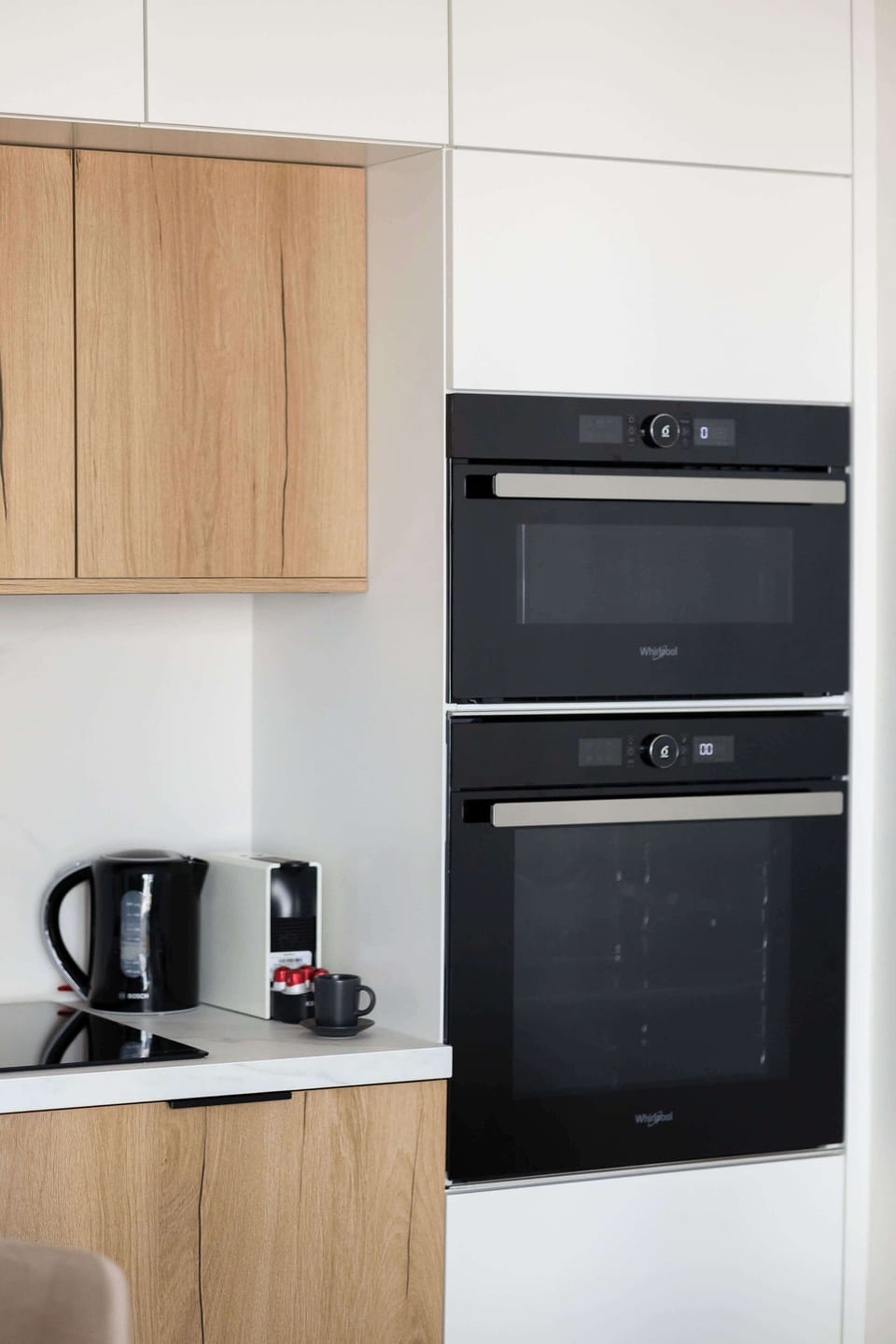 A vertical shot showcases the high-quality built-in black oven and microwave integrated into the kitchen cabinetry.
