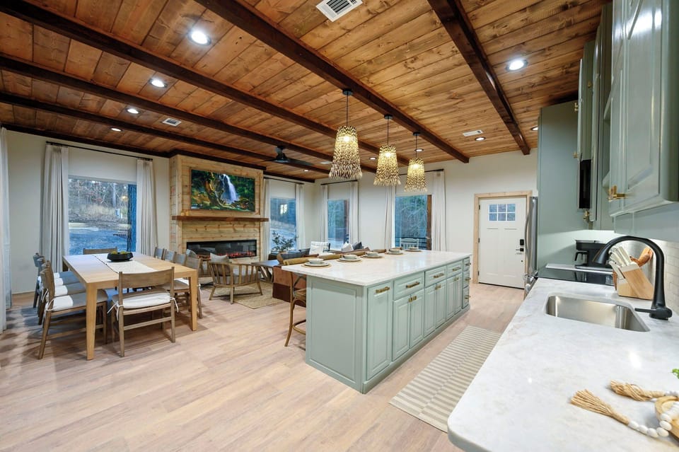 Bright, designer open-concept kitchen & living space with warm wood ceilings — perfect for gathering.