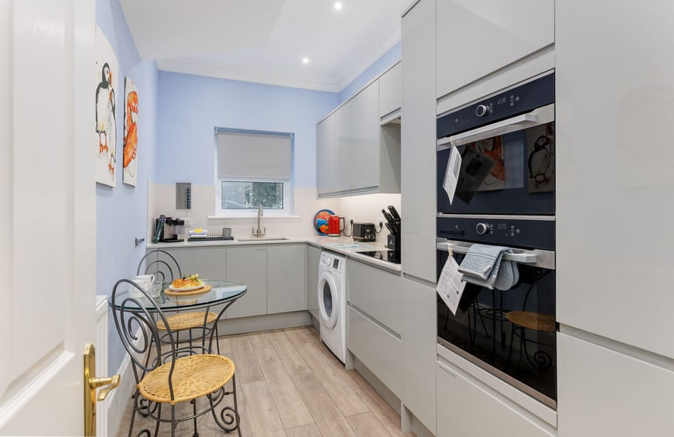 Enjoy a fully equipped kitchen at Cowes Garden Apartment with modern appliances, ample storage, and a stylish dining area for self-catering stays.