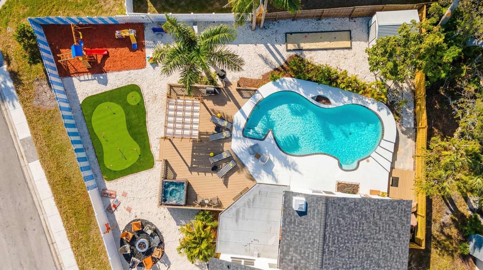 Backyard paradise with a resort-style pool, putting green, hot tub, and plenty of space to relax or play under the palms