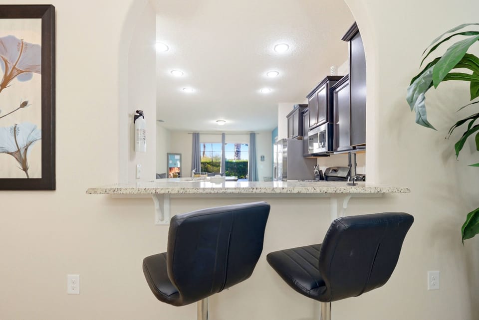 Welcome to the stylish kitchen with sleek black bar stools and an elegant granite countertop, ideal for casual meals or morning coffee.