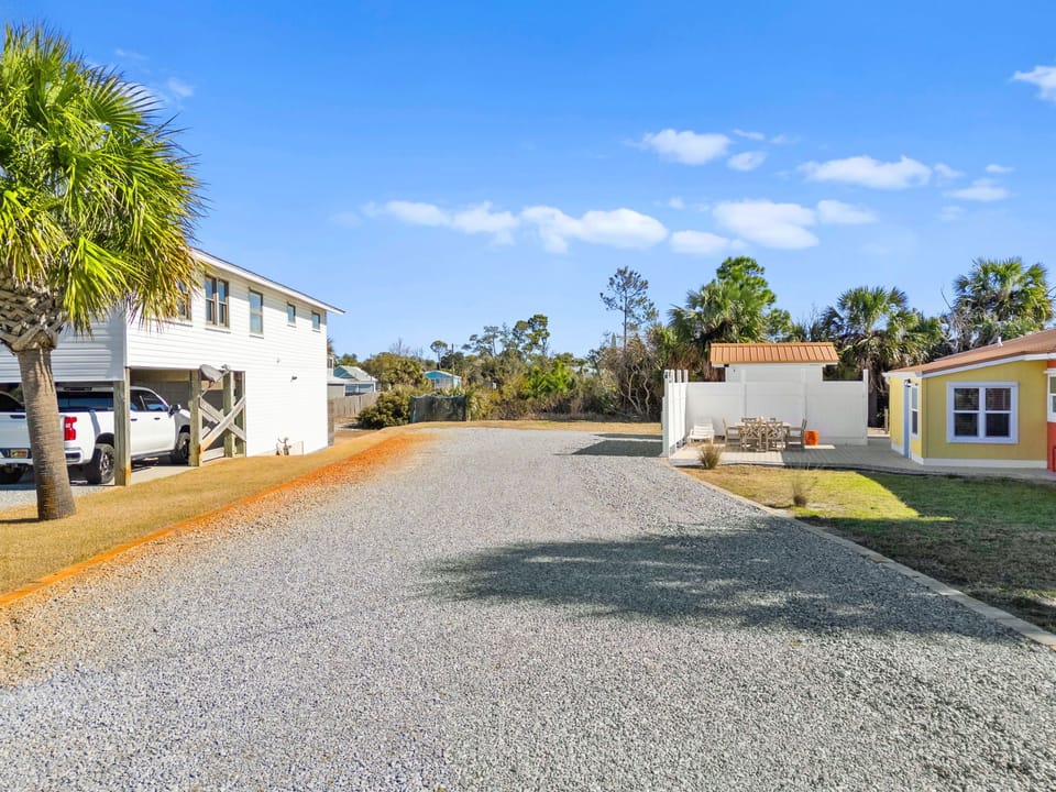 Spacious gravel parking area with tropical palms and colorful beach house accommodations under clear Florida skies.