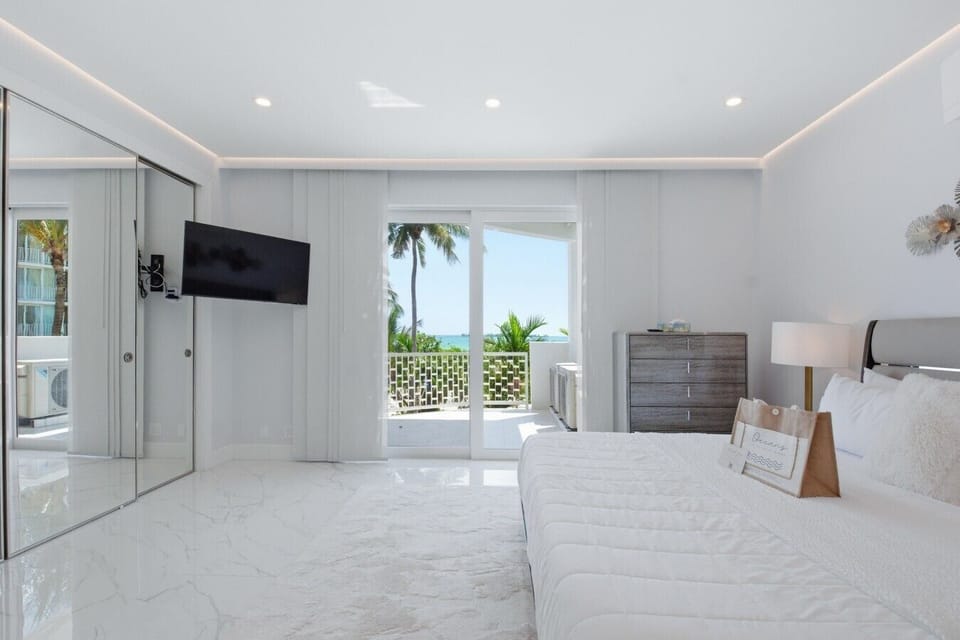 Sleek Coastal Elegance: A spacious, sun-drenched bedroom featuring custom cove lighting and seamless indoor-outdoor flow.