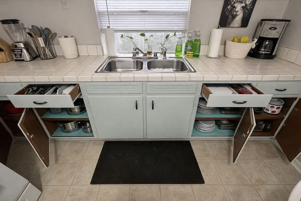 Fully stocked kitchen with cookware, dishes, and utensils.