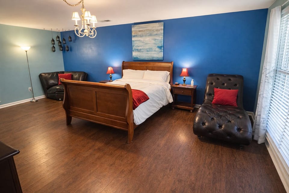 Bright, spacious primary bedroom with TV, natural light, a sitting area.