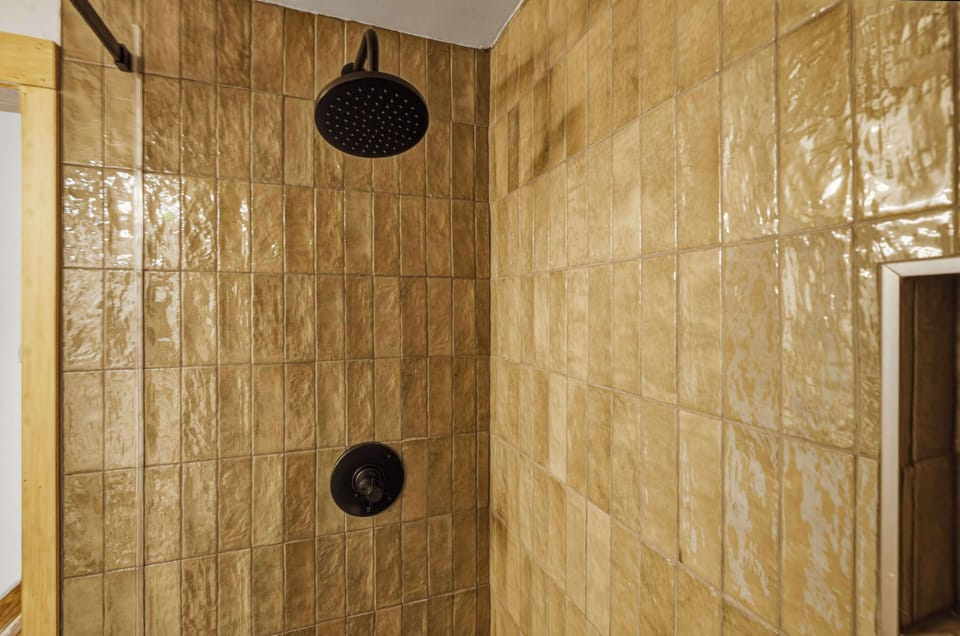 A spa-inspired rain shower wrapped in warm, textured tile and sophisticated fixtures.