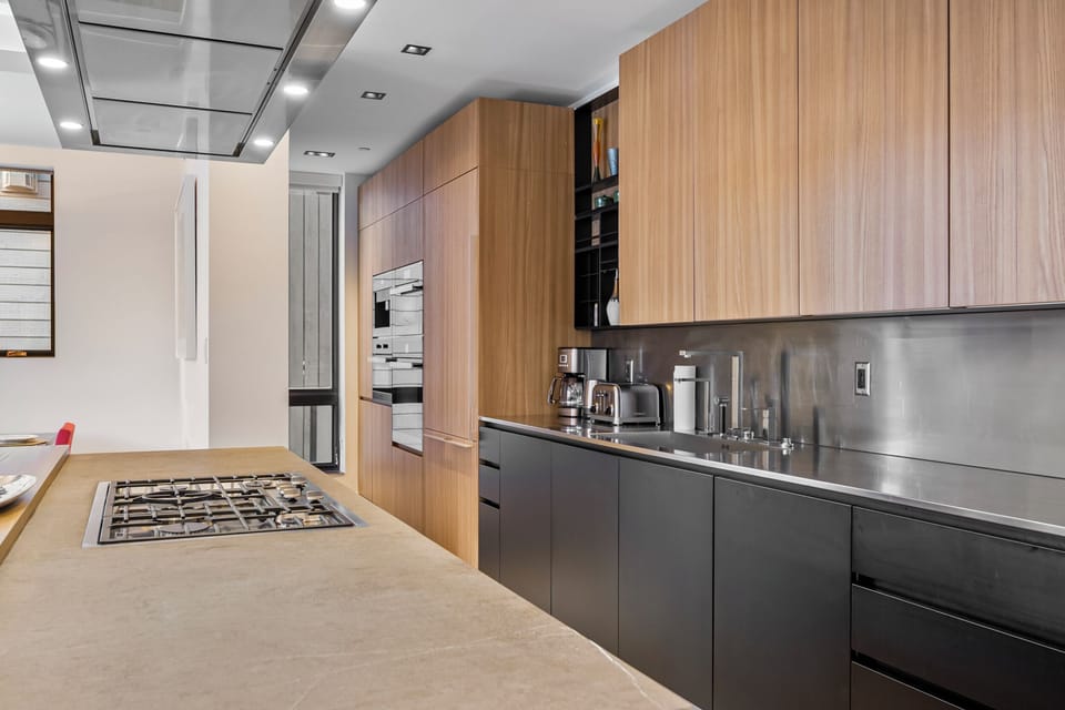 Your sleek kitchen awaits with warm wood cabinets, premium appliances, and a spacious island perfect for culinary adventures and morning coffee.