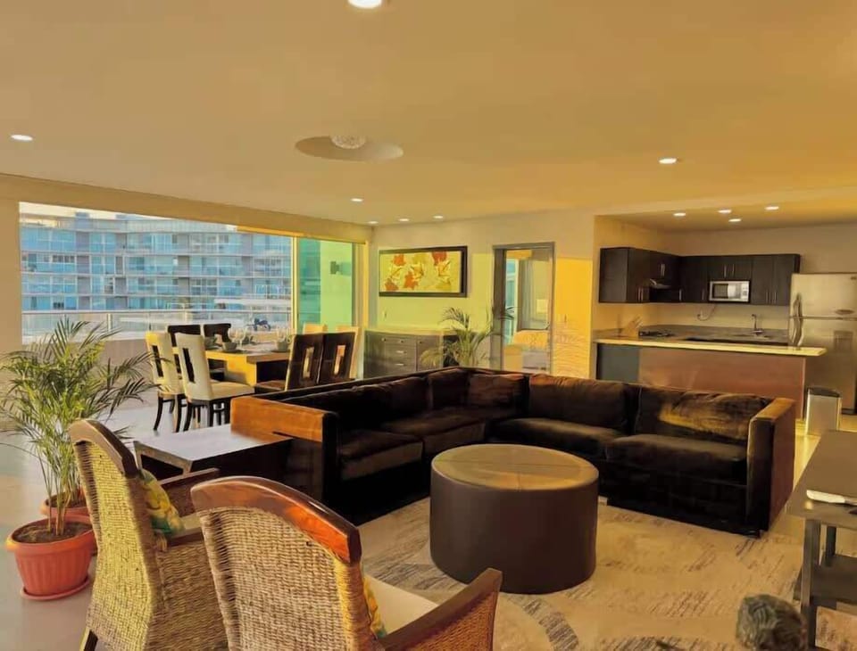 Open living room w/ plush seating, warm lighting & large windows that brighten the space