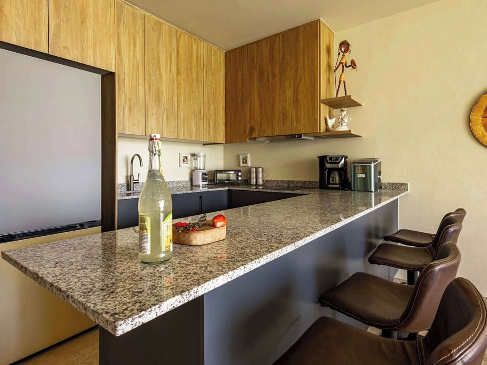 Sleek kitchen island w/ bar seating, stone countertop & open shelving accents