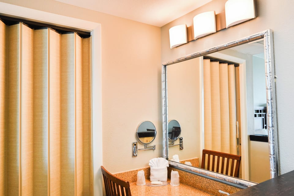 Vanity area with a granite counter, large mirror, and a folding accordion door.