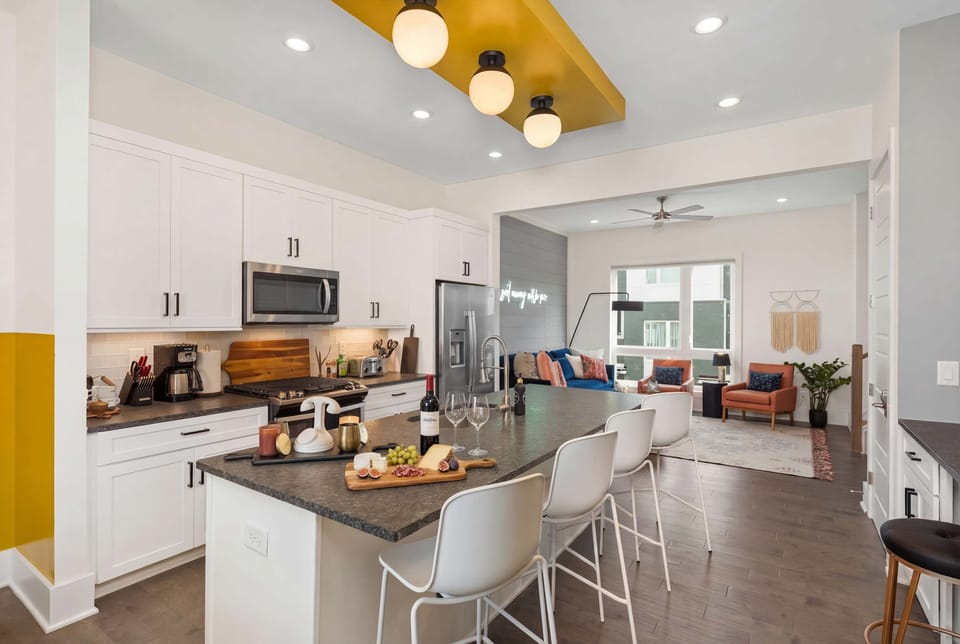 Kitchen island with bar seating flows into the living room, so the cook stays connected to the group. Stainless appliances and breakfast-bar setup make gatherings feel easy. Reserve your Nashville stay with Misfit Homes and start mornings here with coffee in hand