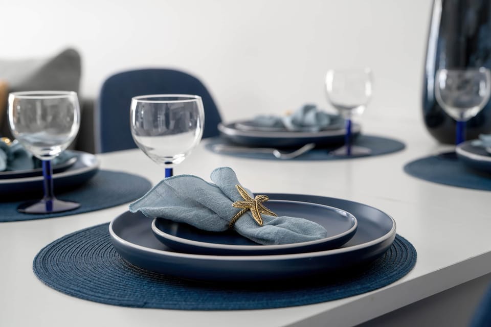 A detailed close-up of a dining setup with dark blue plates, bowls, and wine glasses. The table styling feels elegant and coordinated. Subtle decorative elements enhance the presentation.