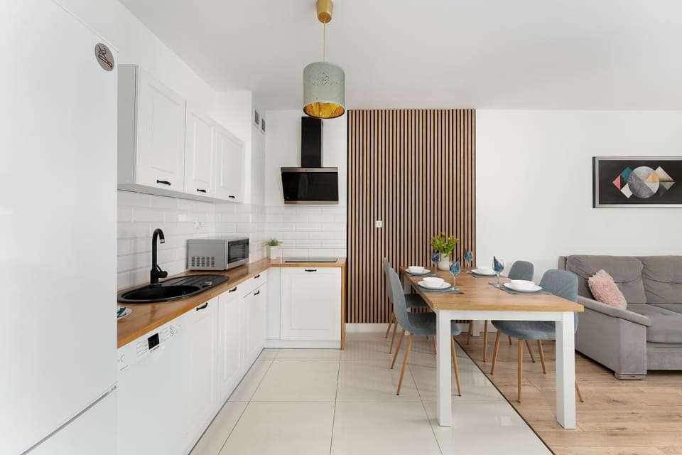 The dining area features a sturdy wooden table surrounded by four comfortable blue chairs. It is perfectly positioned between the functional kitchen and the relaxing lounge.