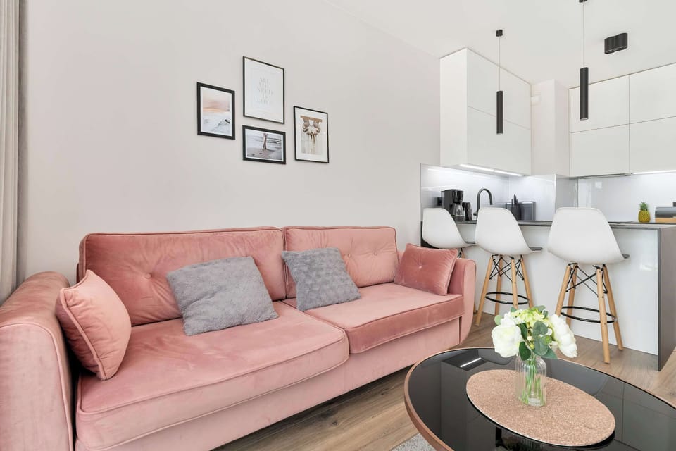An open-concept layout seamlessly connects the loung area with a modern dining space featuring white bar stools. Trendy pendant lighting hangs above the kitchen island, adding a touch of industrial chic.