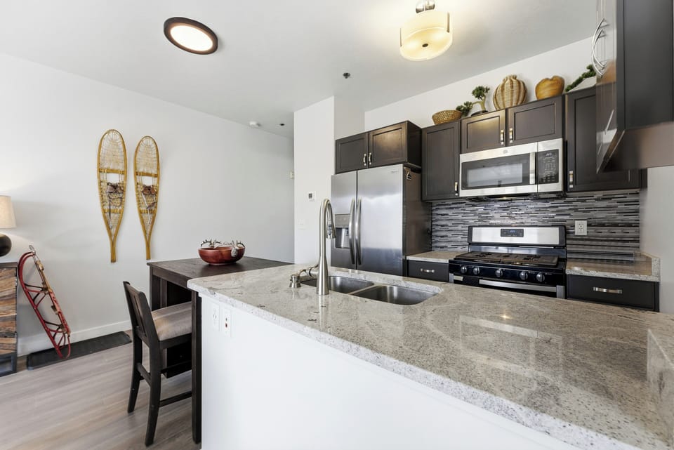 Modern kitchen with granite countertops and stainless appliances inside The Mason luxury condo.