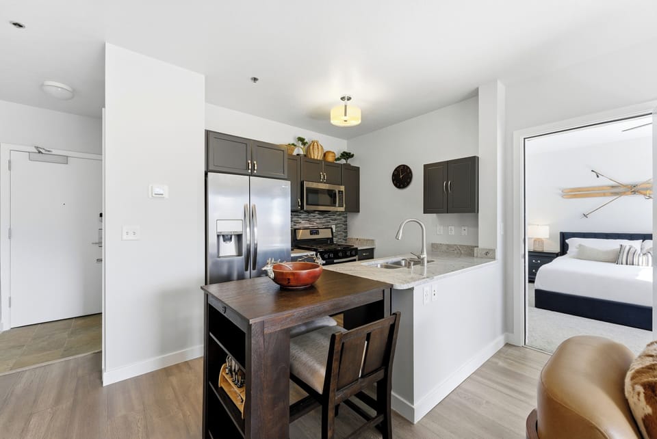 Contemporary kitchen with stainless steel appliances and breakfast bar inside The Mason luxury condo.