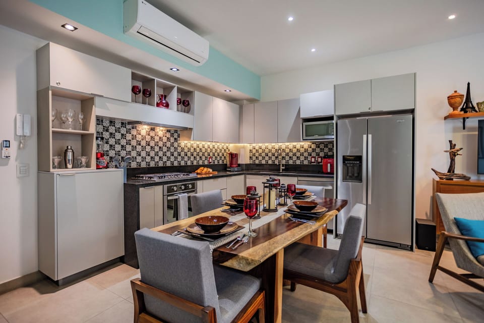Cook and dine in your modern, fully-equipped kitchen featuring sleek appliances, stylish mosaic backsplash, and intimate dining space for memorable meals.