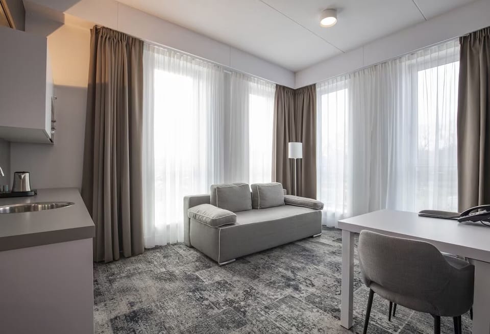 Relax by floor-to-ceiling curtains in a calm, airy lounge.