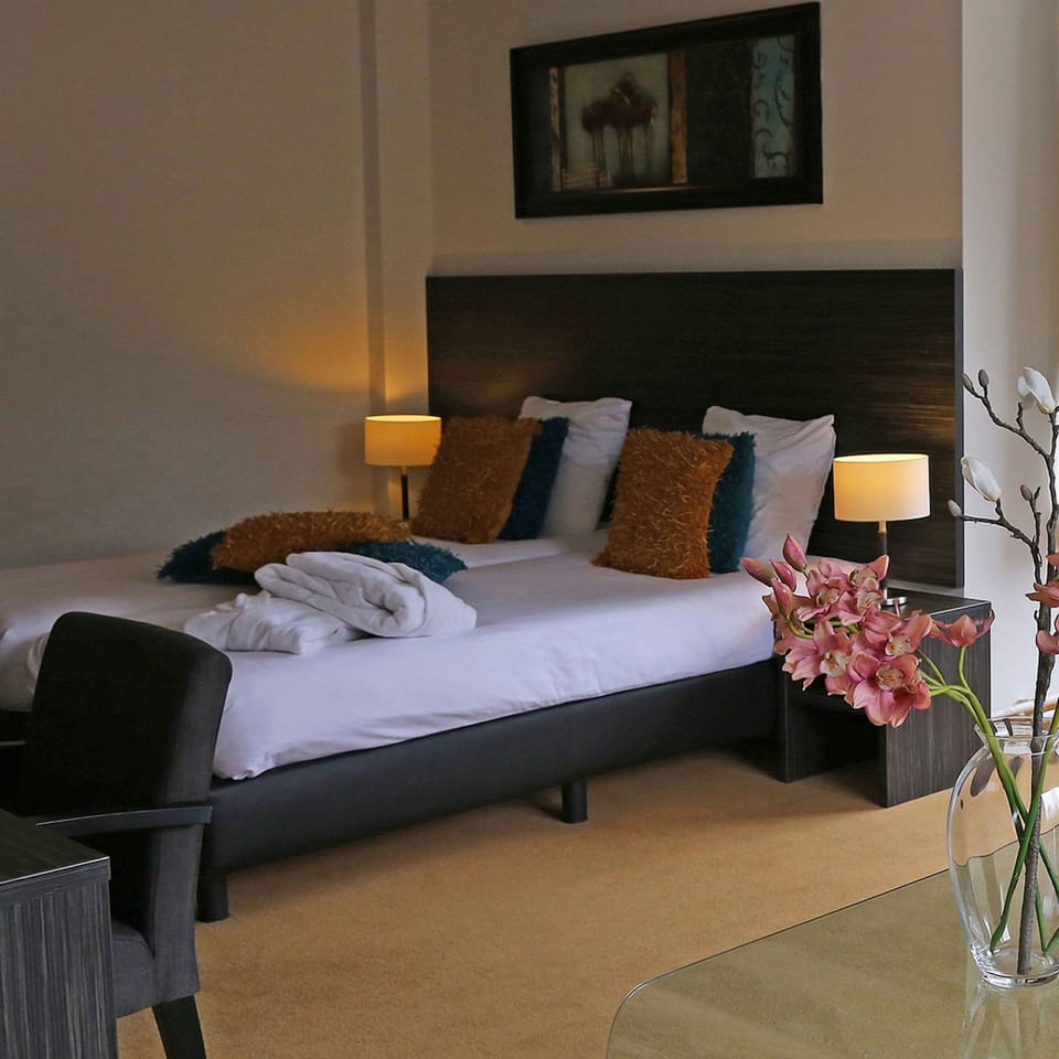 Drift off in plush bedding with soft bedside lighting.