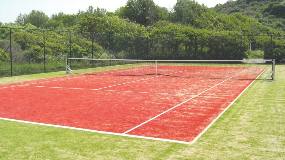 Serve and rally on the resort tennis court, surrounded by greenery.
