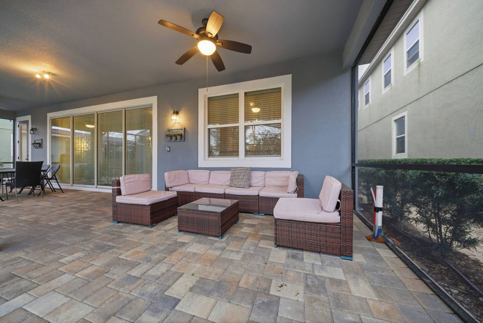 Step onto your private covered patio with a cozy pink sectional sofa and lovely stone floor. Enjoy the gentle breeze from the ceiling fan as you share stories or sip drinks in this welcoming outdoor oasis.