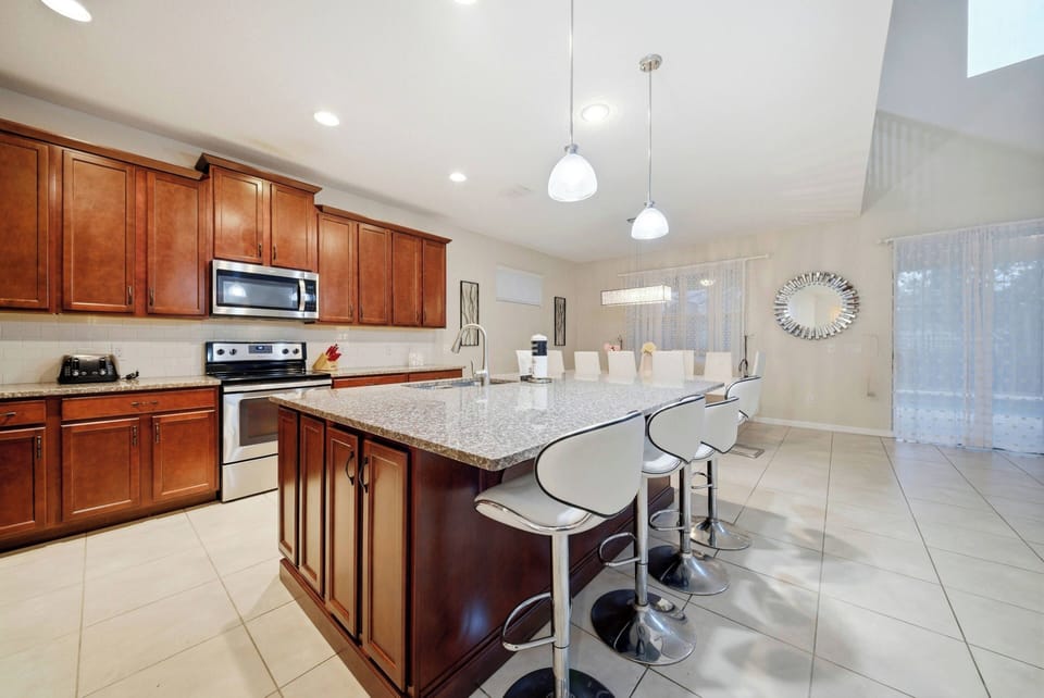 This bright and spacious kitchen boasts rich wooden cabinetry and sleek stainless steel appliances, creating a warm, contemporary atmosphere. Enjoy casual meals or morning coffee around the stylish island with modern bar stools.