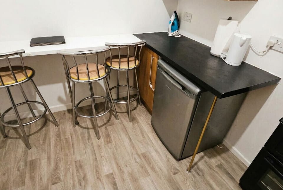 Bar-height breakfast counter with stools, mini fridge, kettle, and iron all within easy reach.