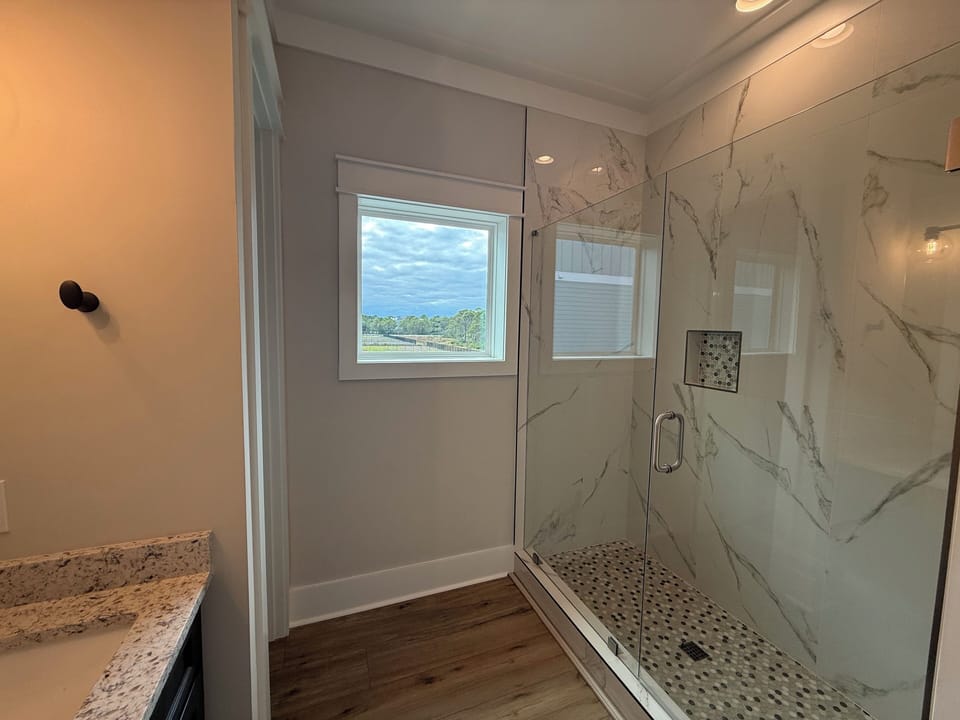 Step into your luxurious marble-walled shower with panoramic windows that frame peaceful countryside views while you refresh and rejuvenate.