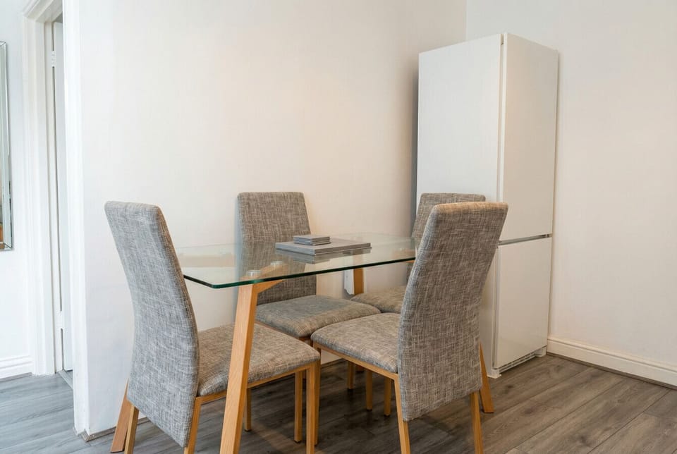 Glass dining table for four with a full-size fridge freezer steps away.