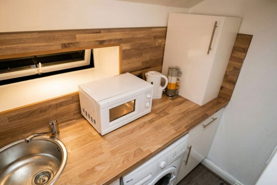 Kitchen counter with microwave, kettle, and a washing machine tucked underneath.
