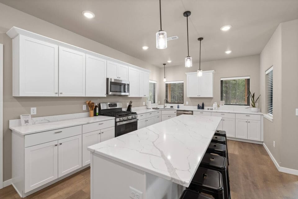White cabinetry, light wood floors, and abundant natural light make this kitchen both practical and inviting.