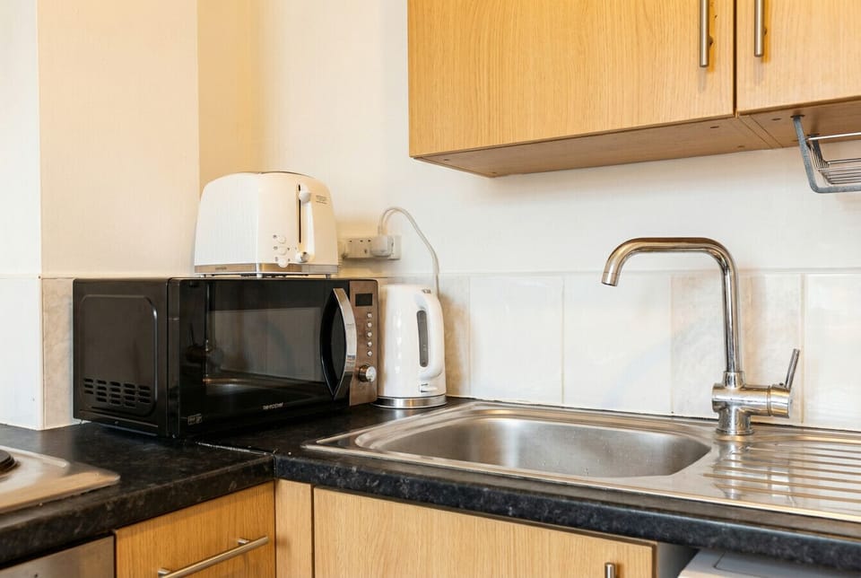 Counter space stocked with microwave, toaster, and kettle for easy mornings.