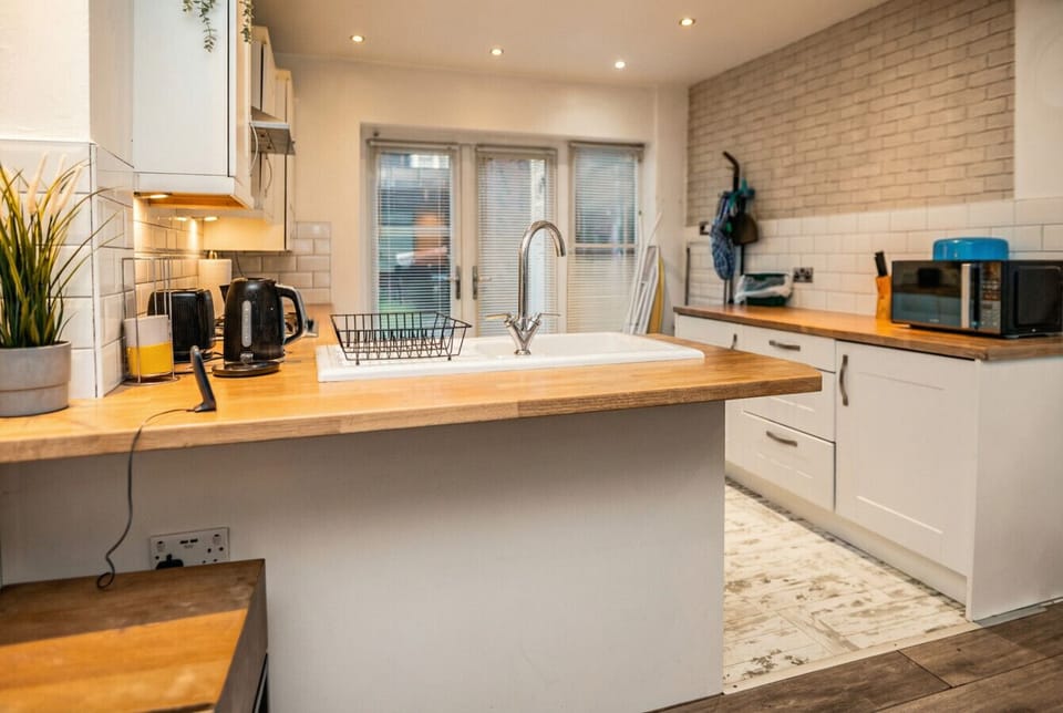 Well-stocked kitchen with wood counters, gas hob, and garden-facing French doors.