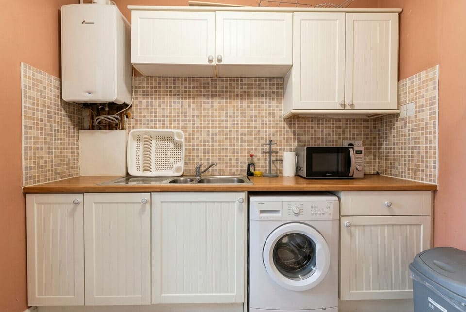 Utility wall with washing machine, microwave, and sink, ideal for longer stays.